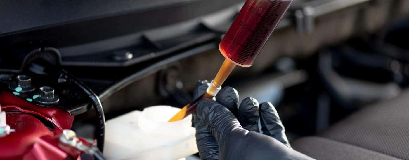 A mechanic is replacing the brake fluid in a vehicle.