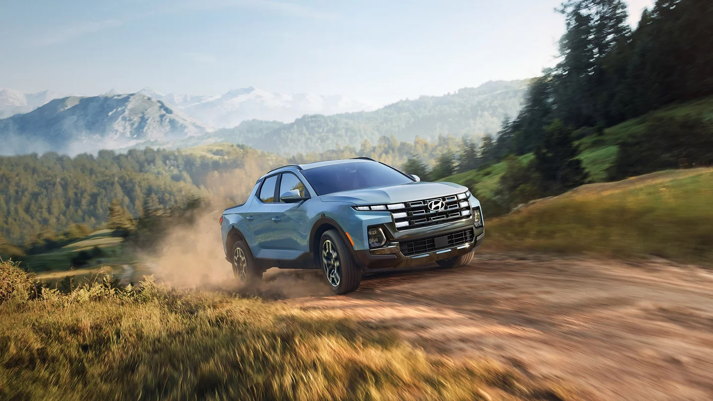 A blue car driving on a dirt road.