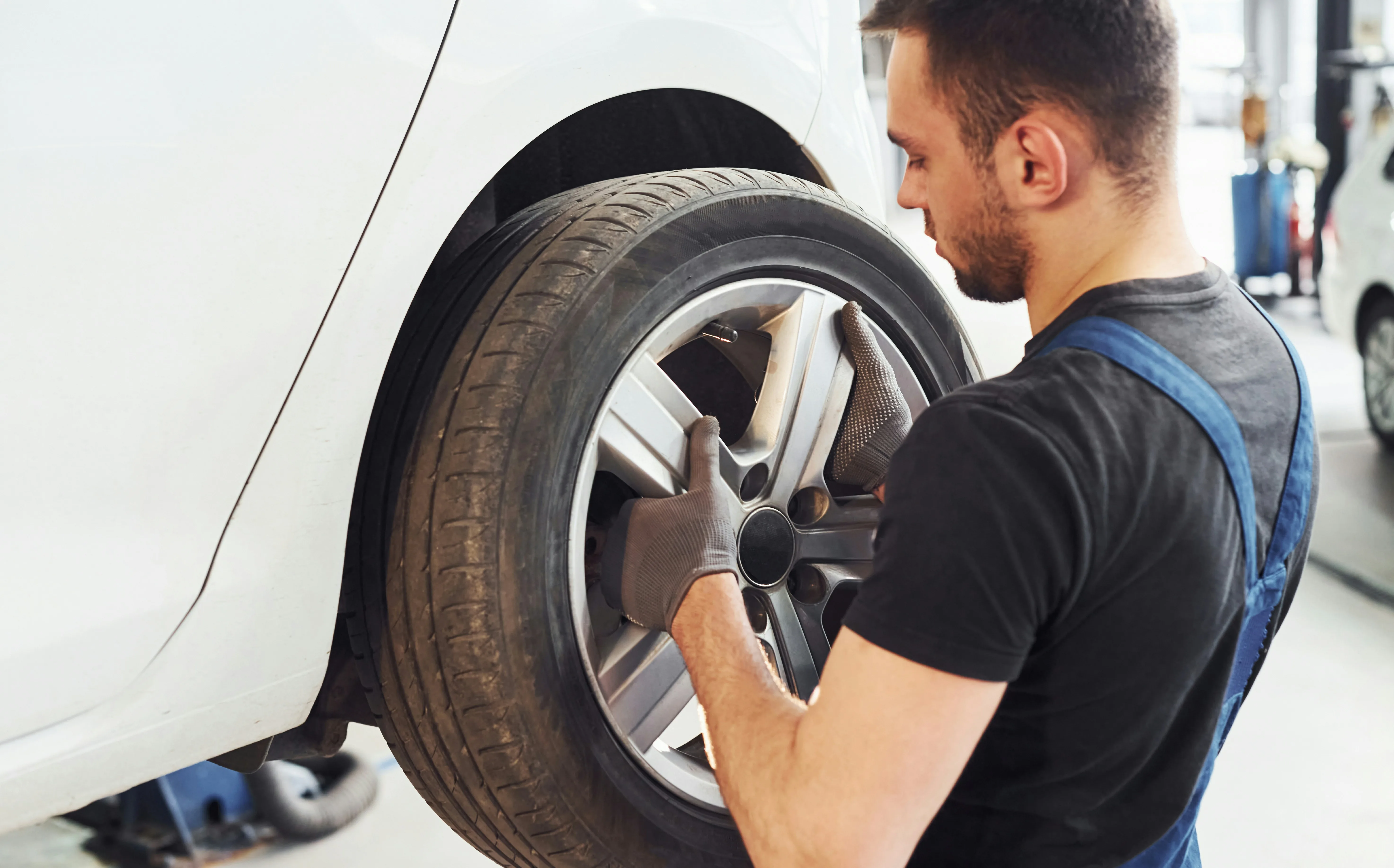 Technician installing a wheel and tire on a vehicle in a service bay
