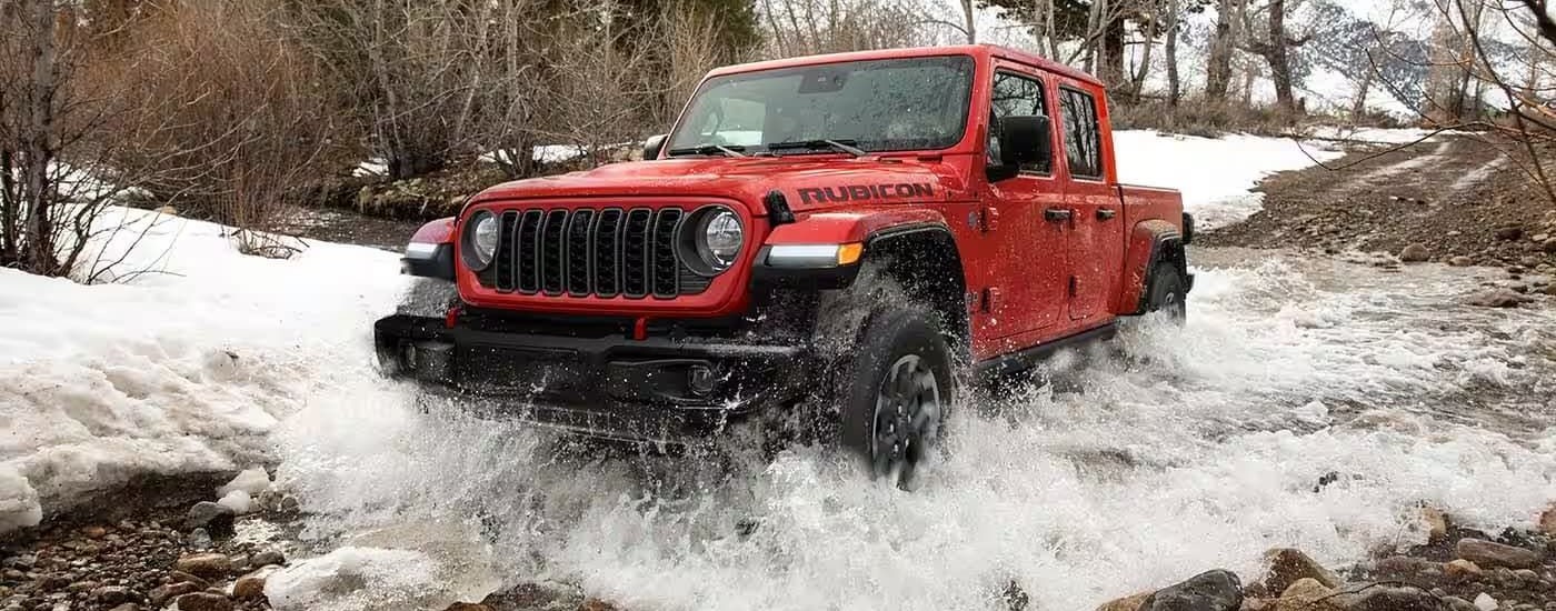 A red 2024 Jeep Gladiator is shown off-road after leaving a Jeep dealer.