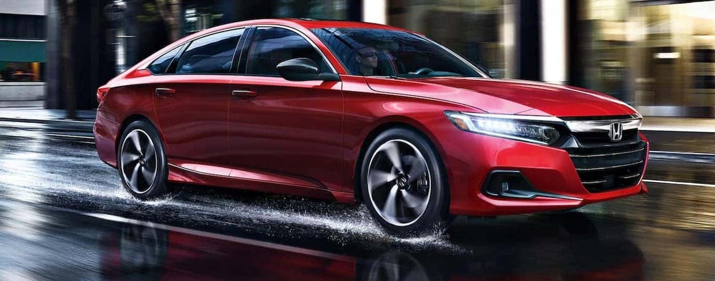 A red 2021 Honda Accord is shown driving on a wet street.
