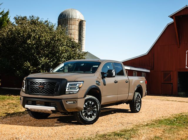 A beige nissan titan xd in a front driver side on a farm.