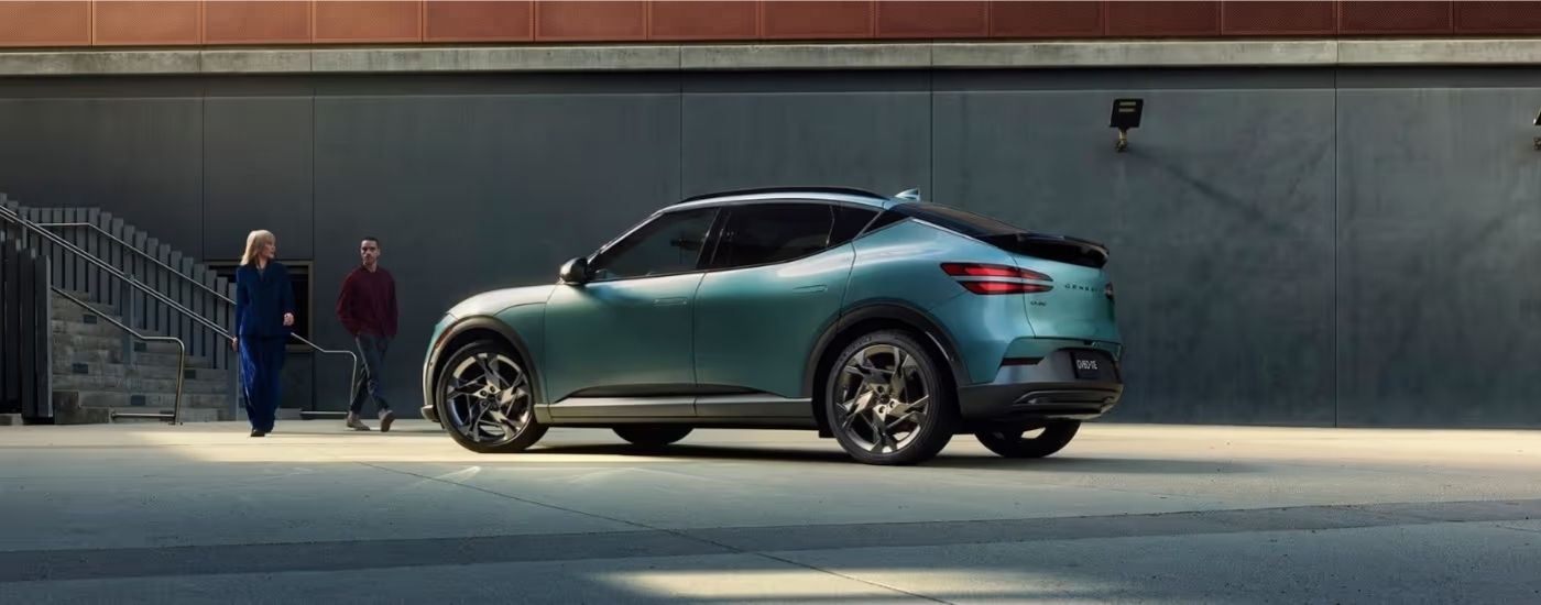 People walking toward a teal 2024 Genesis GV60