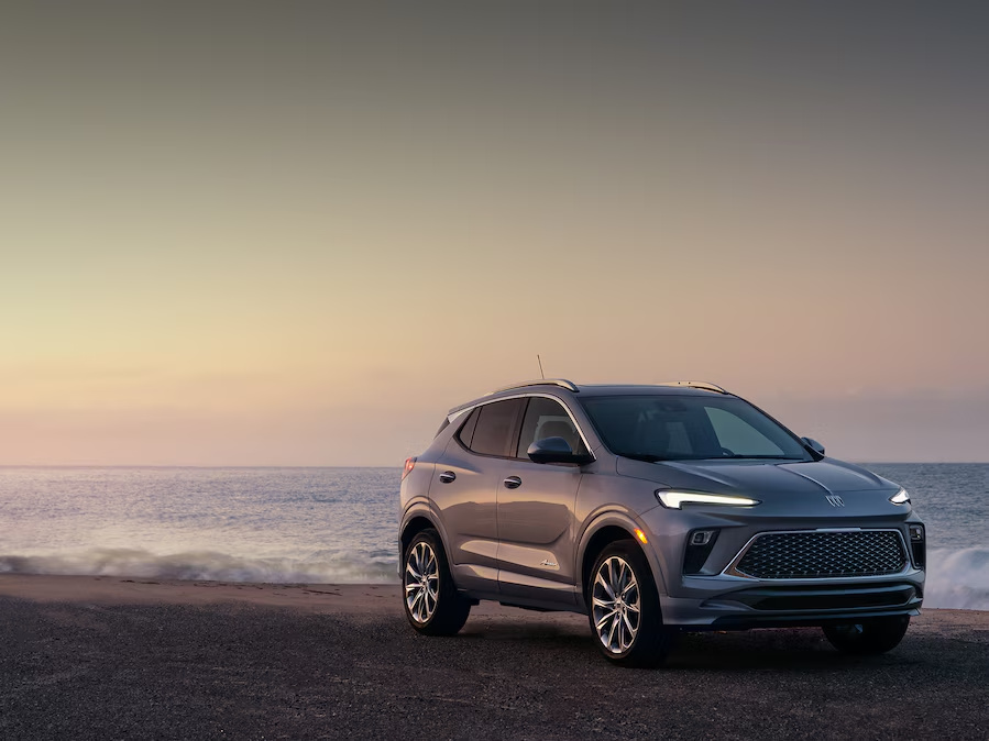 Gray Buick Encore GX Avenir parked on a beach at sunset