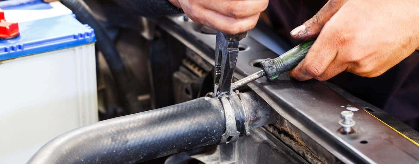 A mechanic is shown replacing a radiator hose.