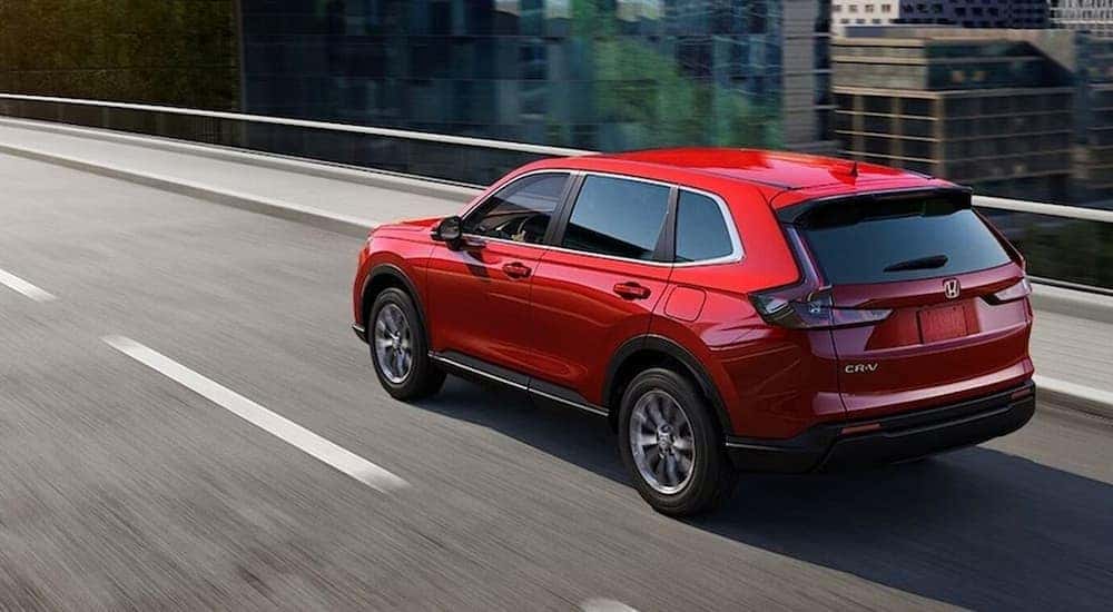 A red 2026 Honda CR-V driving on a highway.