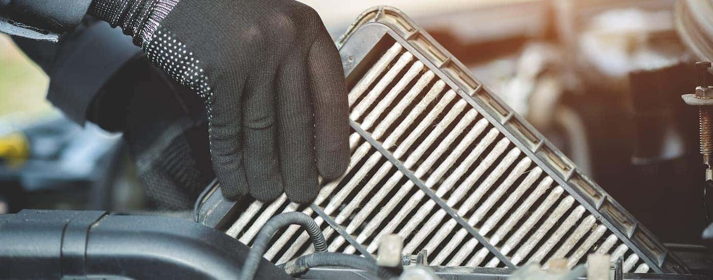 A gloved hand is shown changing an air filter during a Honda service.