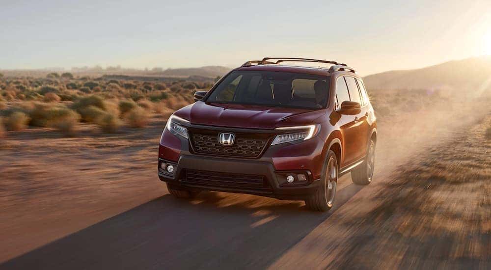 Red 2020 Honda Passport Elite driving on a dusty road.