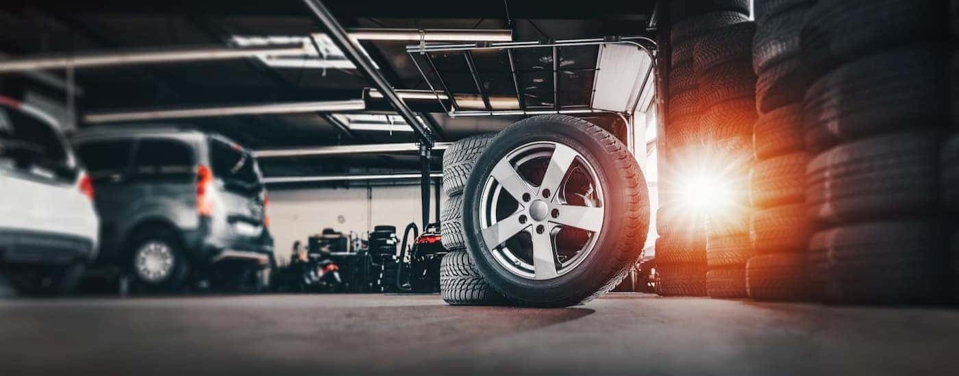 Tires in a garage are shown stacked on a sunny day.