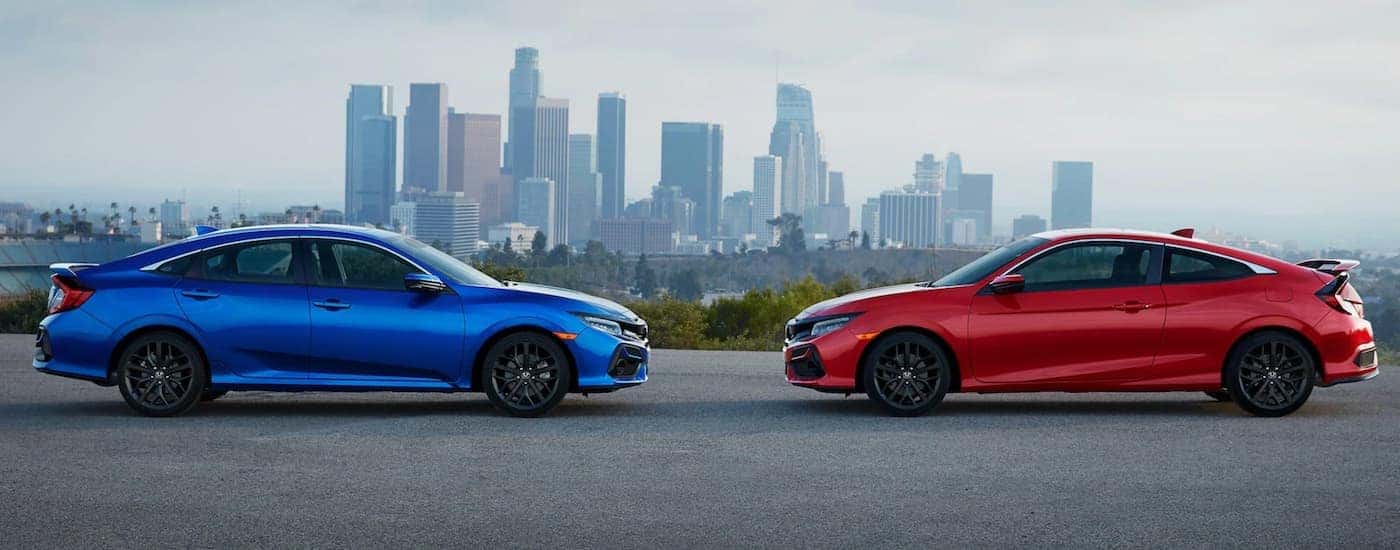 Two Honda cars, a blue 2021 Honda Civic Si Sedan and a red 2021 Civic Si Coupe, are facing each other.