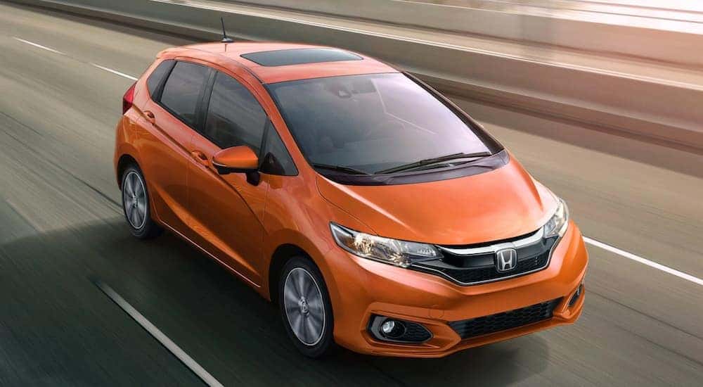 An orange 2021 Honda Fit EX-L is shown from a high angle driving on the highway after leaving an Irondequoit Honda dealer.