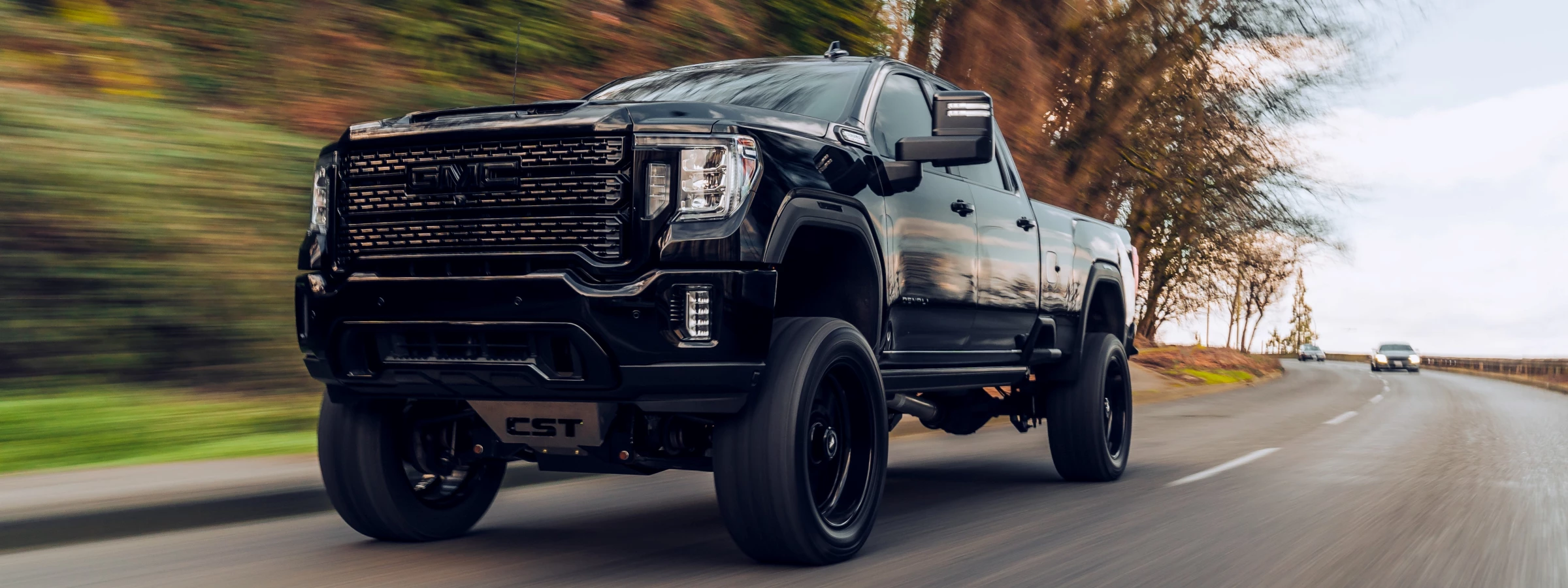 Black lifted GMC Sierra pickup driving on a highway