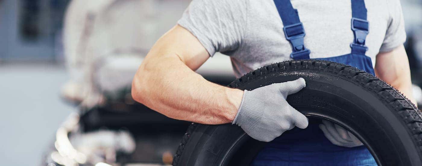 A technician is shown holding a tire.