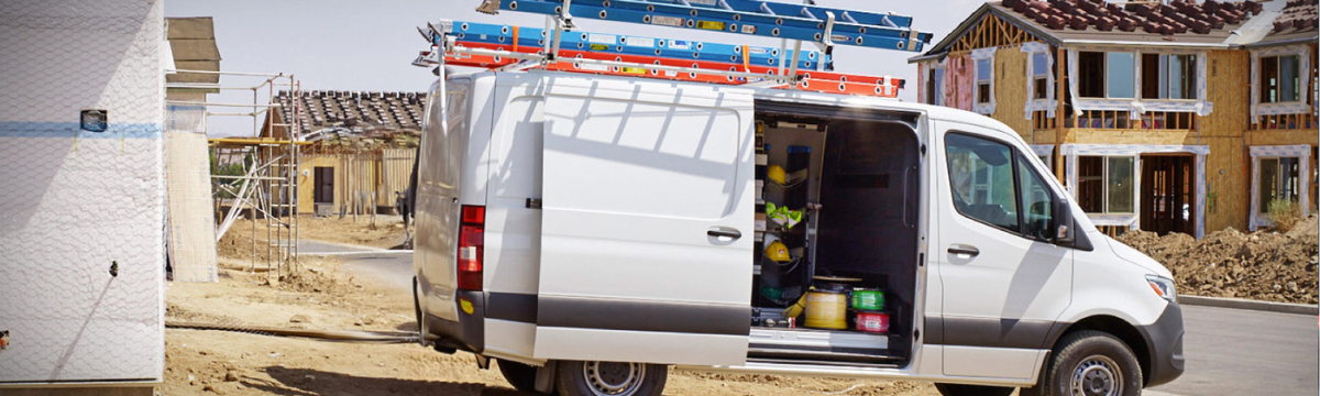 A white Mercedes-Benz Sprinter work van parked at a residential construction site.