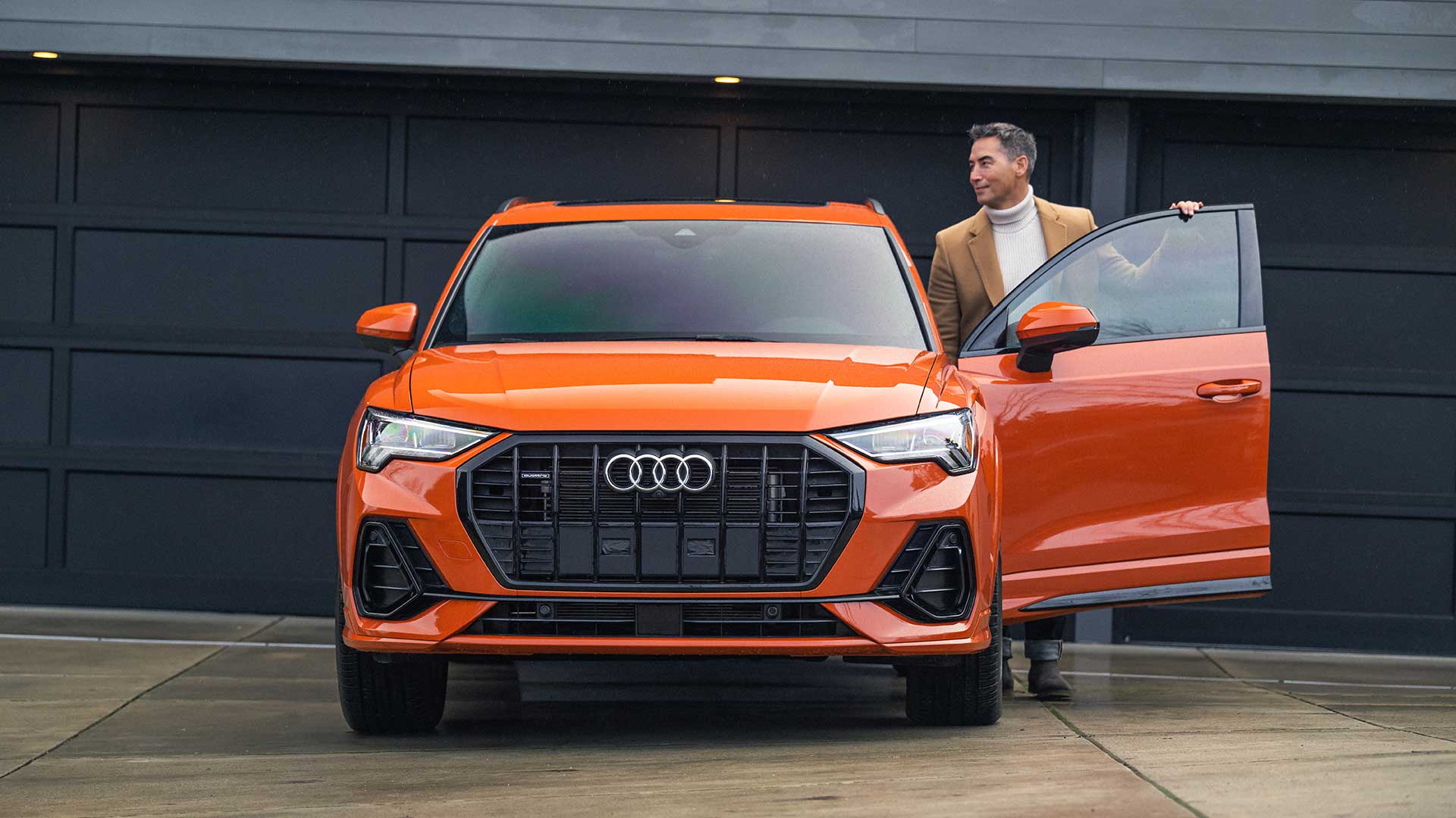 Man stepping into parked Audi Q3 in driveway