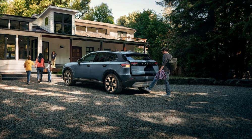 A blue 2025 Honda Prologue parked near a family house.