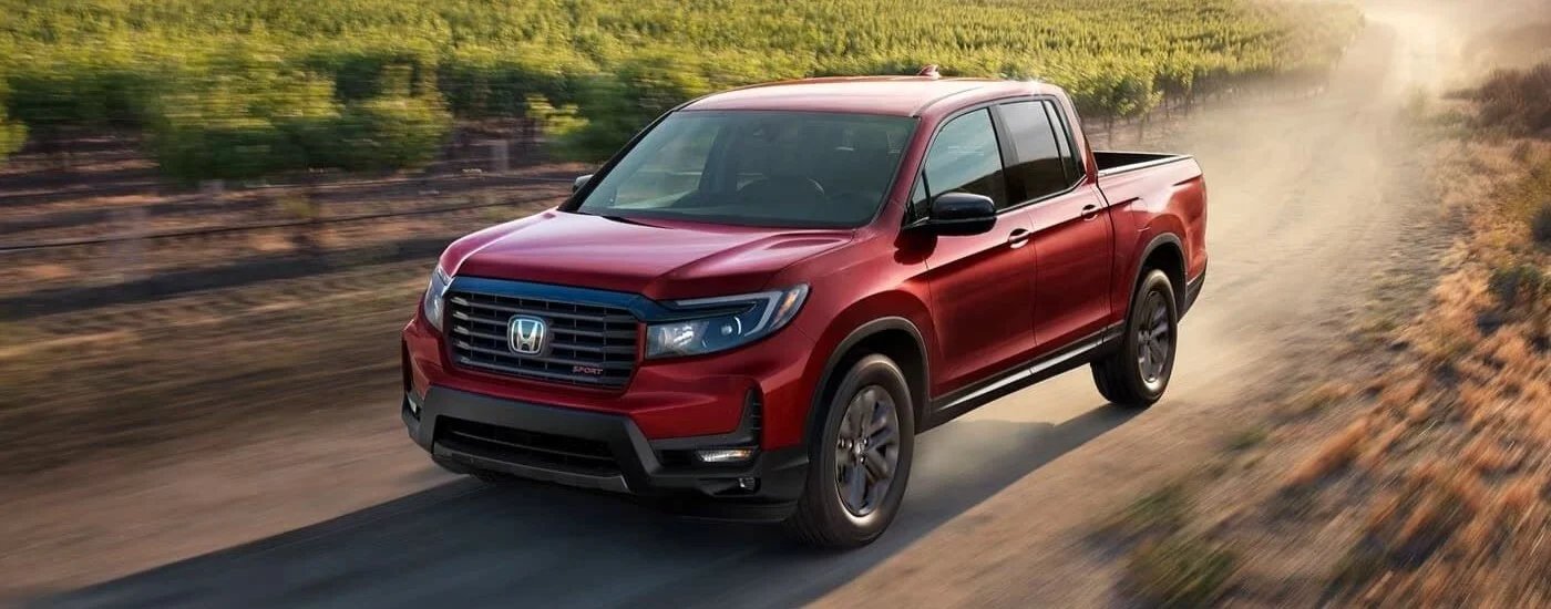 A red 2023 Honda Ridgeline Sport driving off-road.
