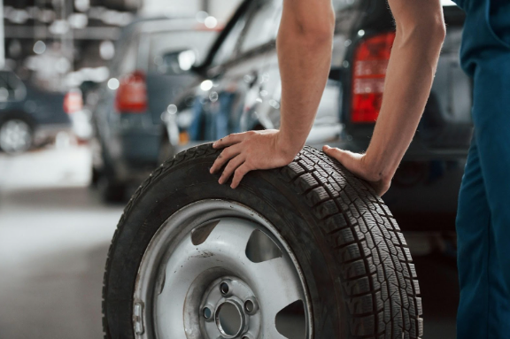 A man holding a tire in his hands.
