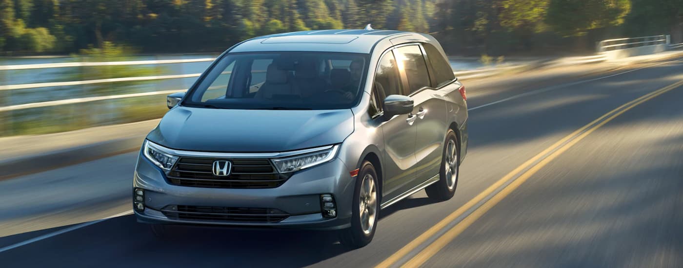 Grey 2024 Honda Odyssey driving down an open road.