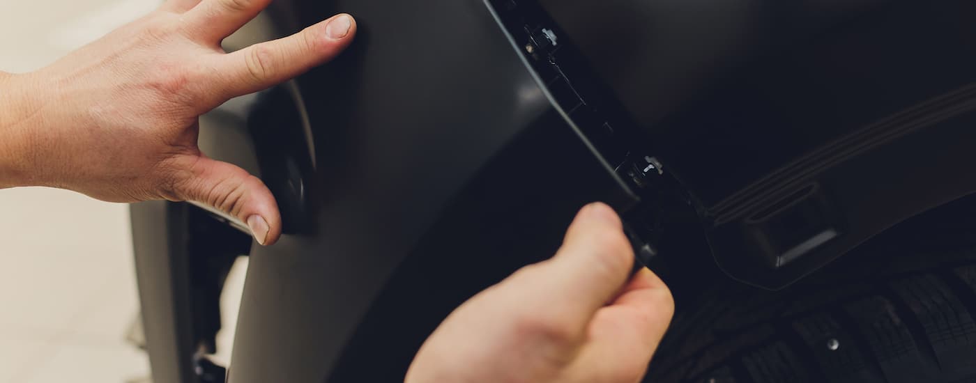 A new black bumper being placed onto a vehicle