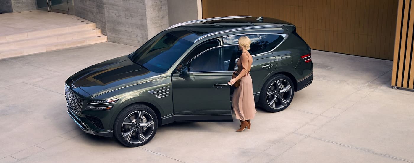 Woman opening the door on a green used 2025 Genesis GV80 for sale