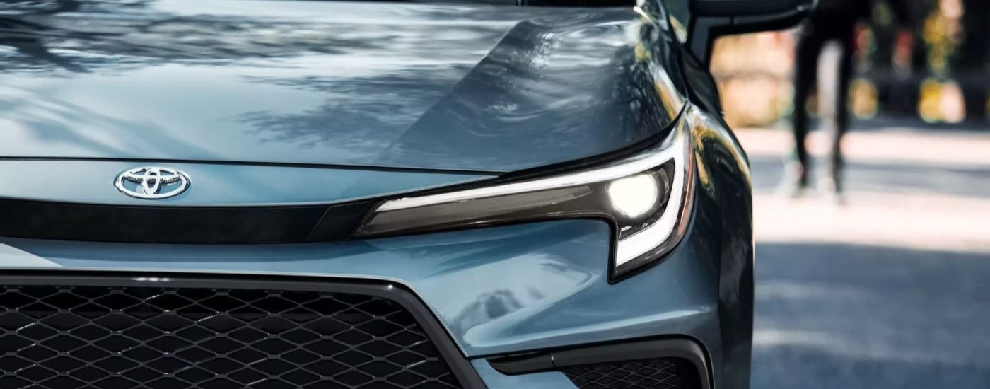 Headlight and grille on a blue 2023 Toyota Corolla XSE.