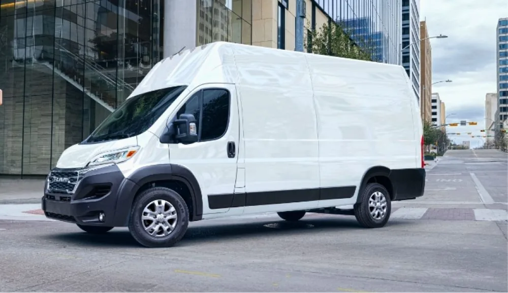 White 2026 RAM ProMaster cargo van parked on a downtown street beside a glass office building