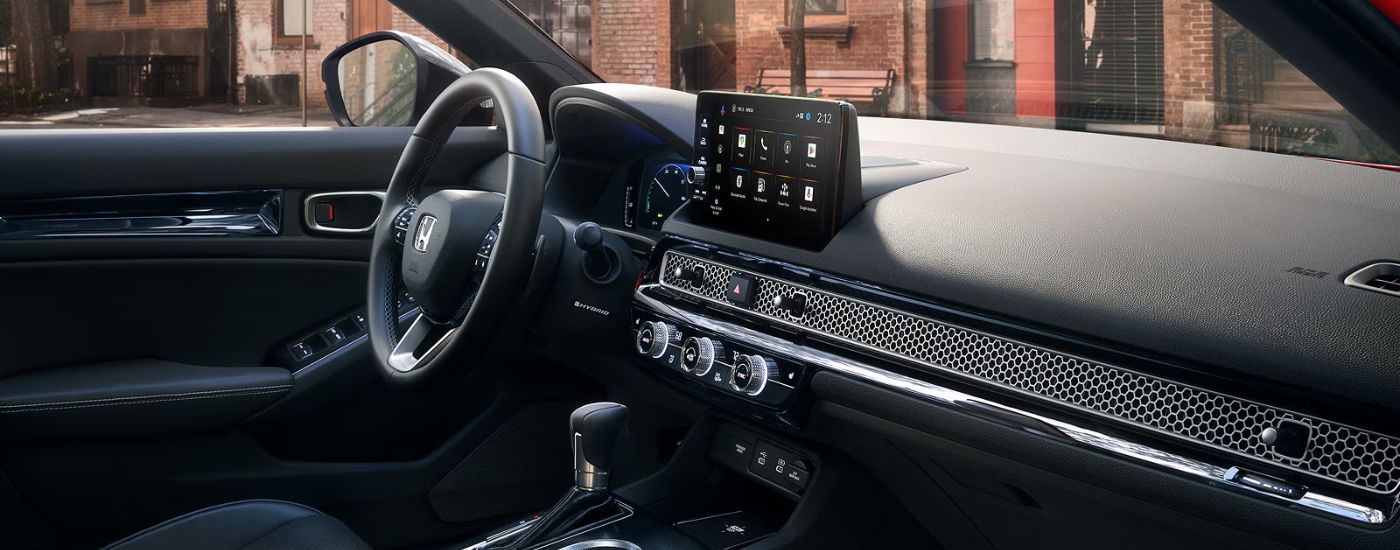Interior view of a 2026 Honda Civic Sport Touring Hybrid infotainment and steering wheel.