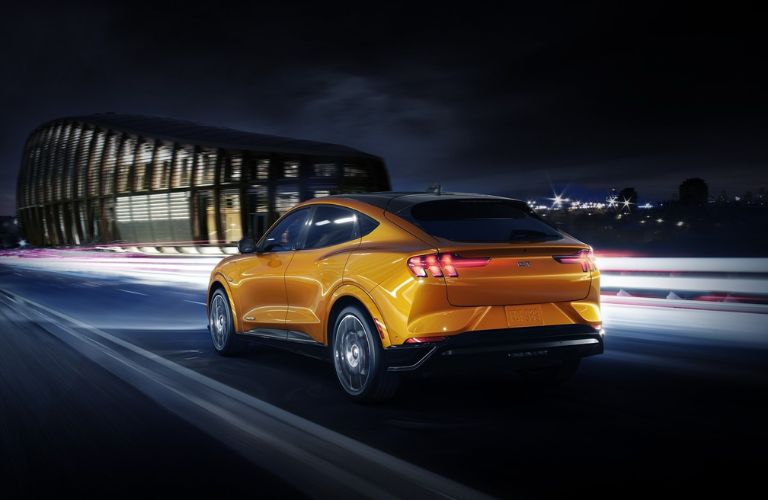 Orange 2022 Ford Mustang Mach-E Rear Exterior on Highway at Night