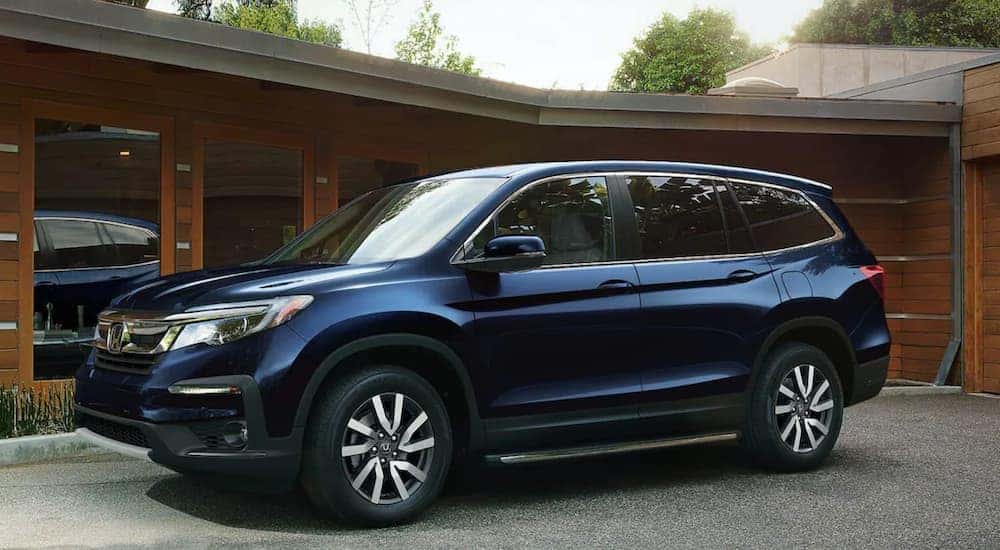 A blue 2021 Honda Pilot EX-L is shown parked in front of a house after leaving a Rochester Honda Pilot dealer.