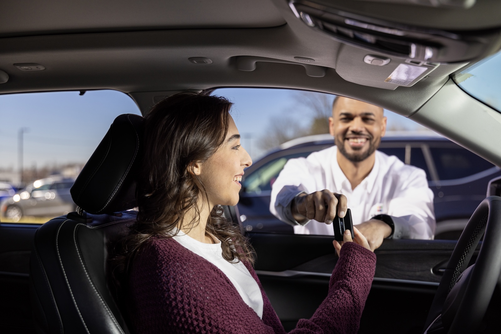 Woman being handed keys while sitting in car