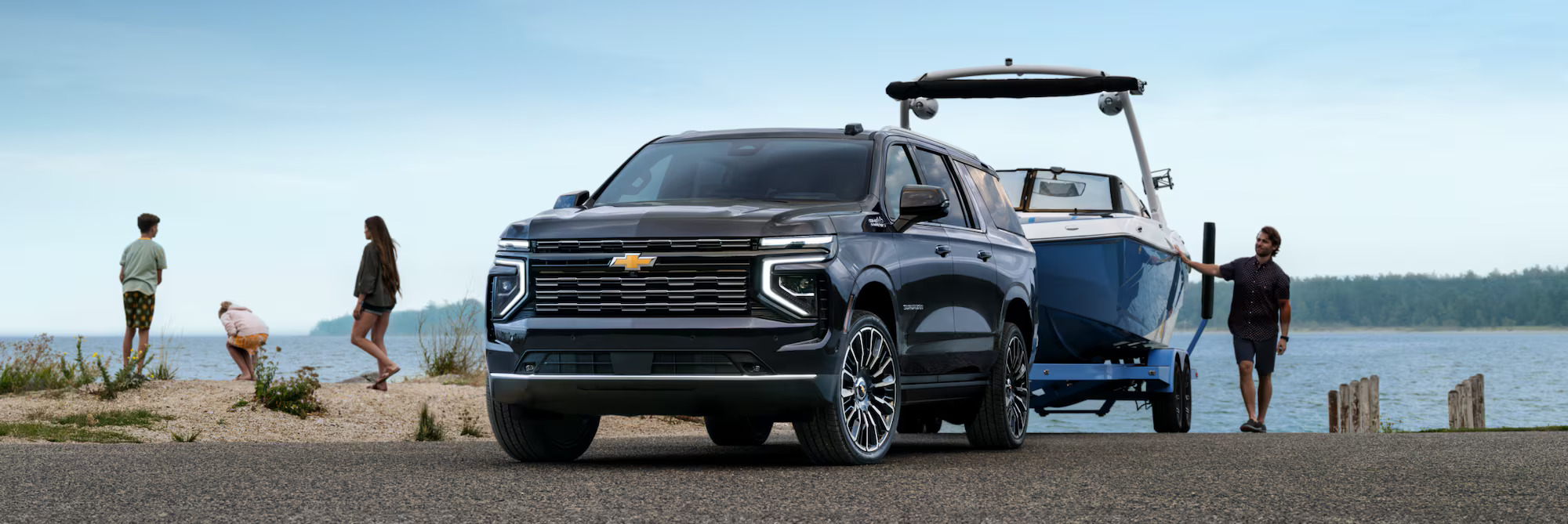 A black suv pulling a boat on a trailer.