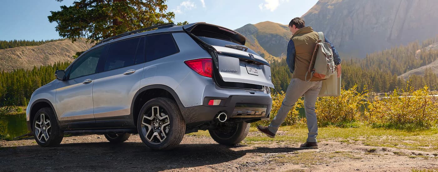 A silver 2023 Honda Passport Elite parked while rear gate is opening.