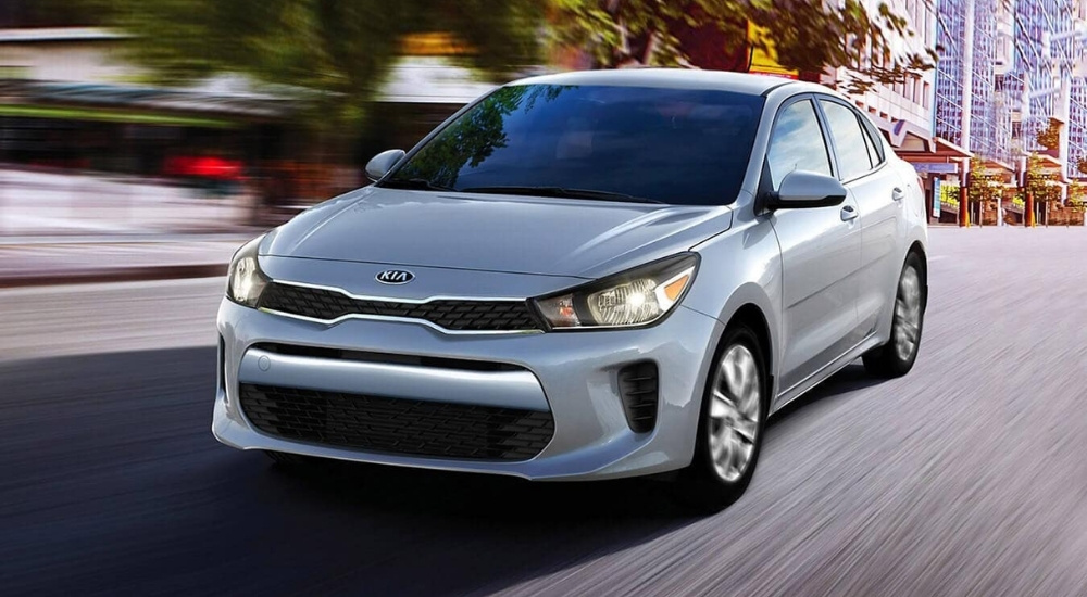 Silver 2020 Kia Rio is shown driving on a city street