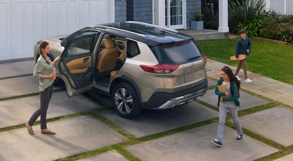 A family entering a tan 2024 Nissan Rogue.