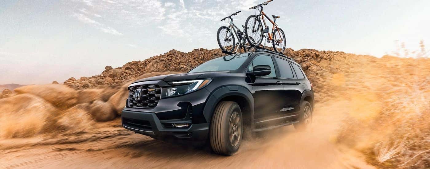 A black 2022 Honda Passport Trailsport is shown off-roading in the desert.
