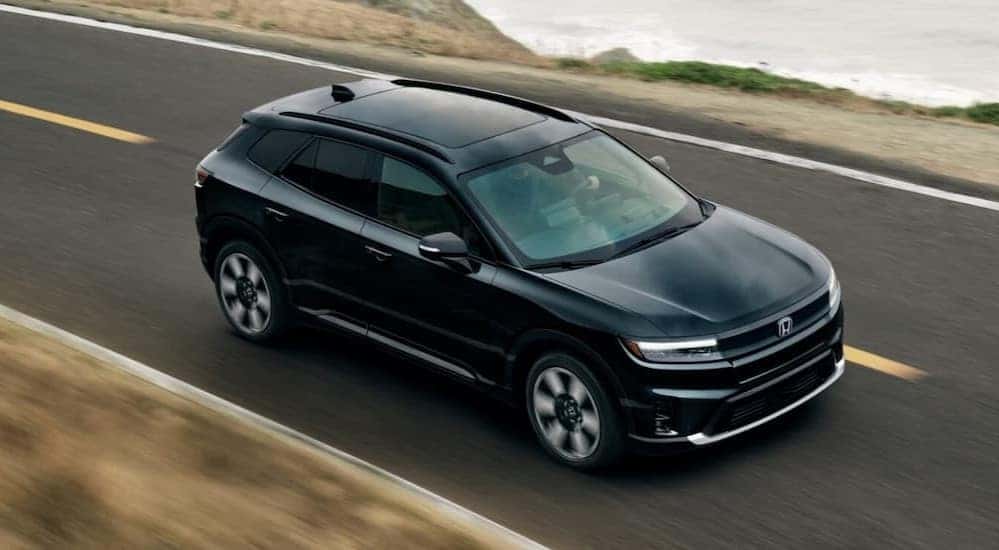 A black 2025 Honda Prologue Elite is shown driving on a highway.