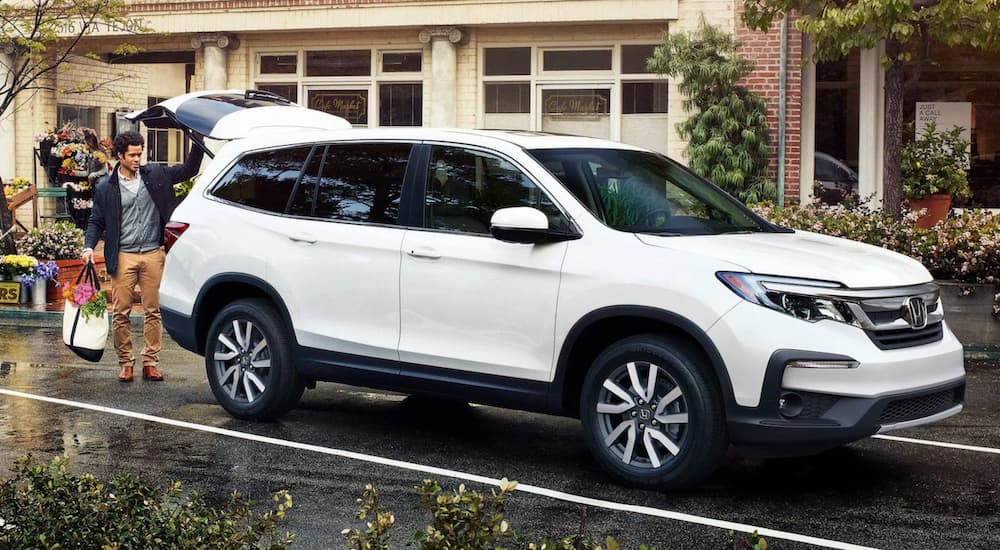 A man loading groceries into the trunk of a white 2021 Honda Pilot EX-L.