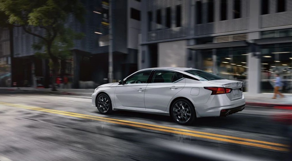 A white 2024 Nissan Altima driving in a city.