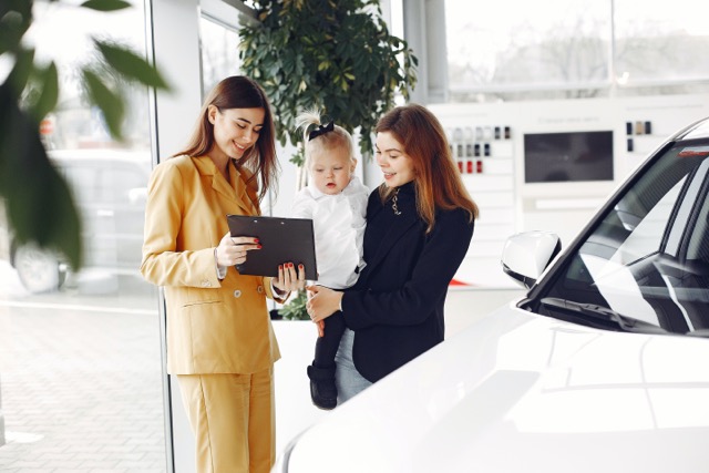 Salesperson showing clipboard to client holding her child