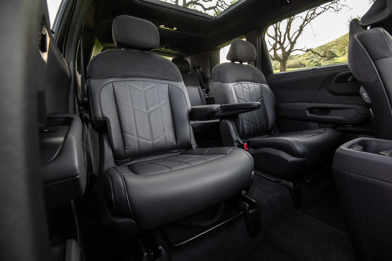 Black leather second-row captain's chairs in the 2027 Kia Telluride X-Pro, with individual armrests and a center console, beneath an open panoramic sunroof.