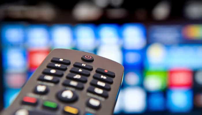 Hand holding a TV remote in the waiting lounge