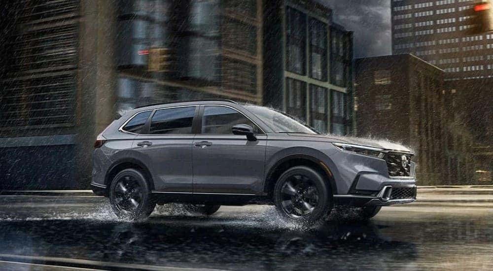 A gray 2023 Honda CR-V Sport Touring is shown driving on a wet road