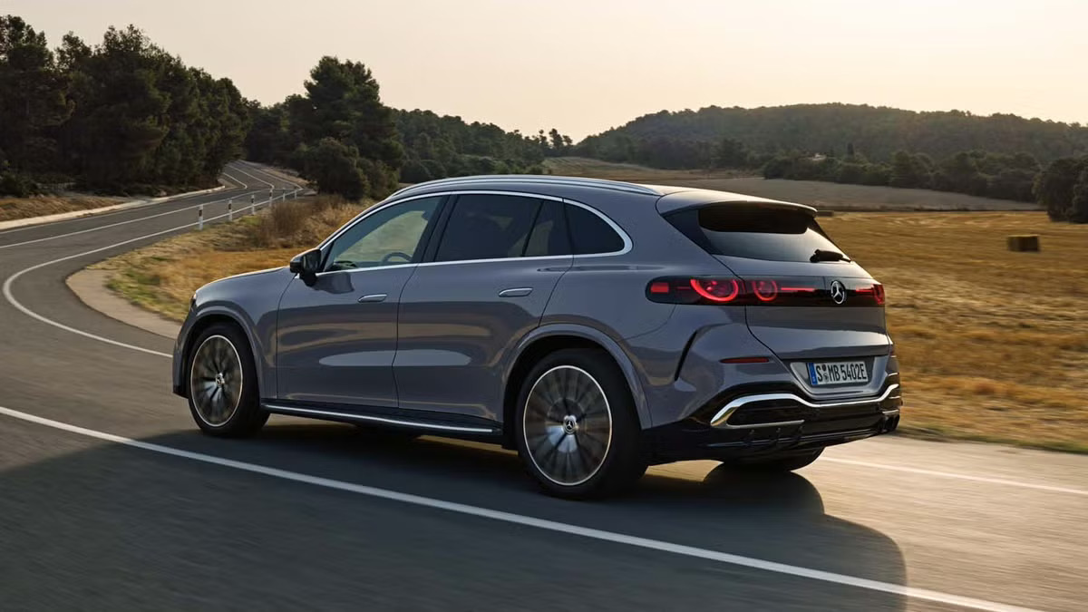2027 Mercedes-Benz GLC electric in gray driving on a country road, rear three-quarter view