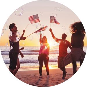 Men and Women on a Beach at Sunset Holding American Flags