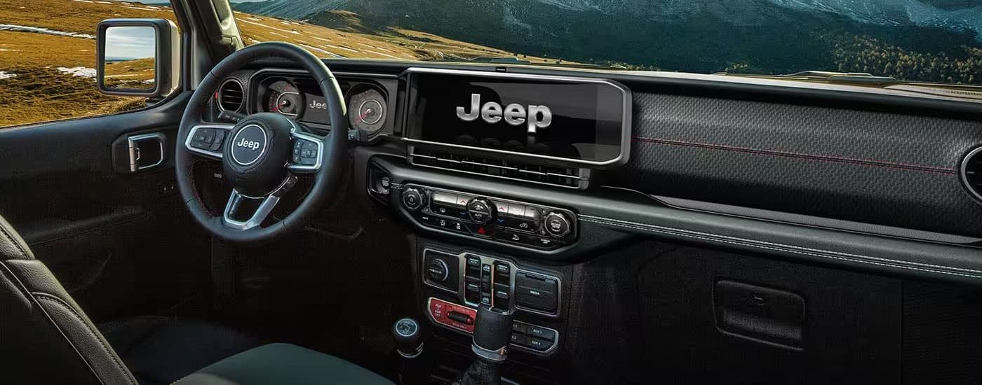 A close up shows the black dash and infotainment screen in a 2024 Jeep Wrangler.