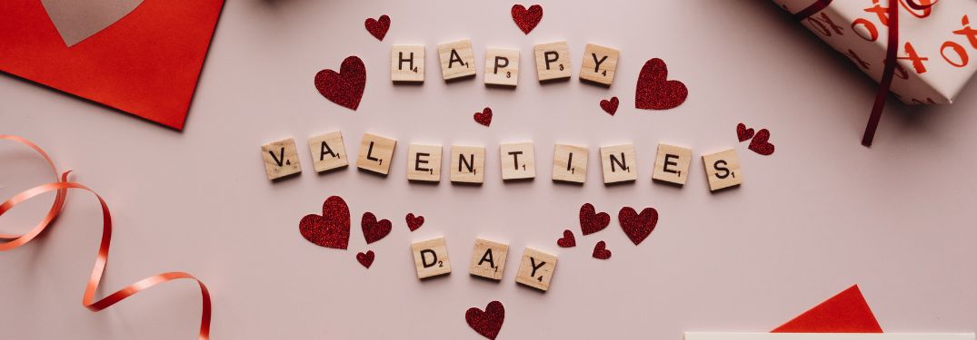 Happy Valentine's Day Scrabble Tiles on Table with Valentine's Day Decorations
