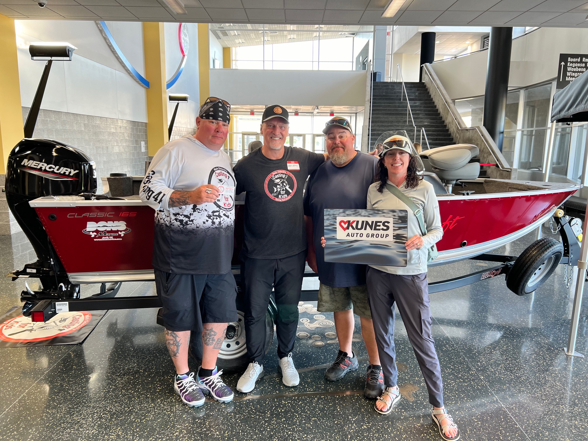 Pictured from left to right: Michael Whitefeather, Mark Osiecki, Brad Scharfenorth, and Carol Scharfenorth in front of the boat that was auctioned off at the Casting for Kids event