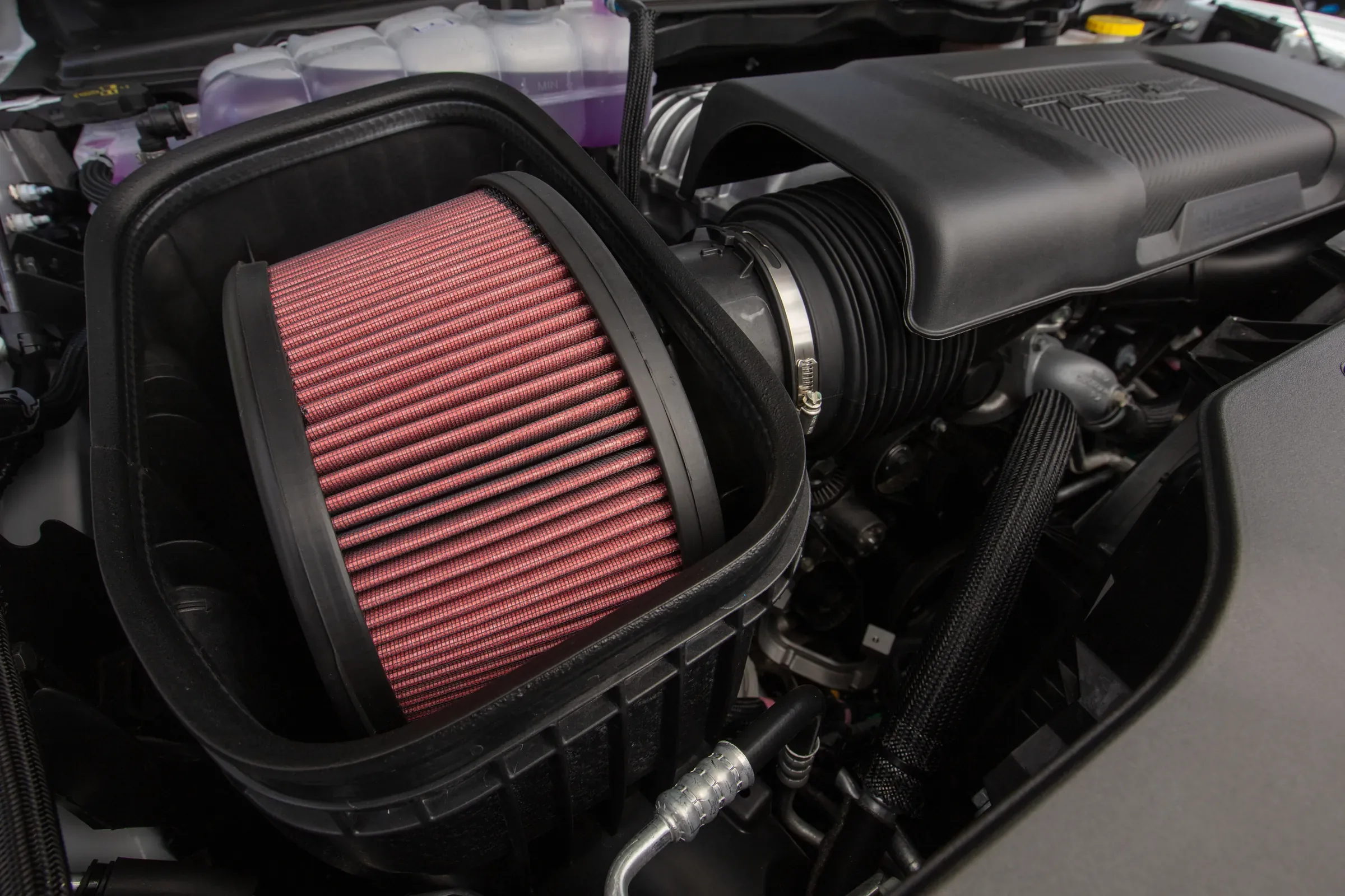 Close-up of a red performance air intake filter installed in a vehicle's engine bay. Engine Air Filter Service Near Kansas City