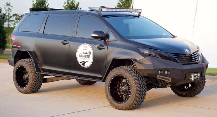Lifted matte black minivan with a roof-mounted light bar